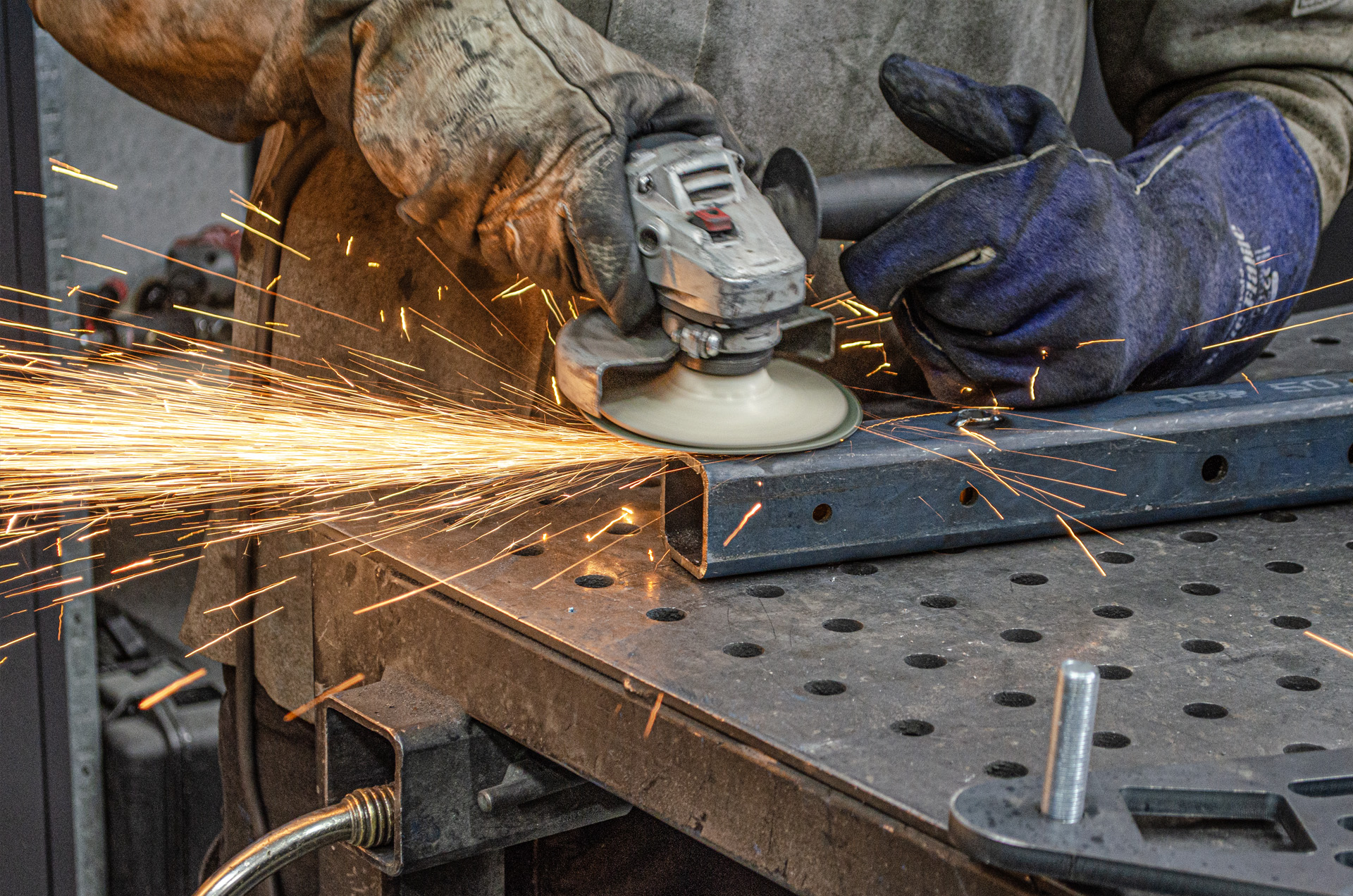 MiWeld fabricator grinding a welded steel section in the Malaga workshop, sparks flying